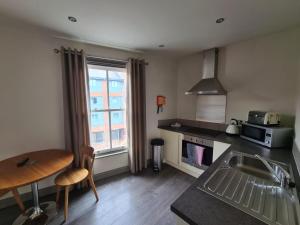 una cucina con lavandino, tavolo e finestra di Base Serviced Apartments - City Road a Chester