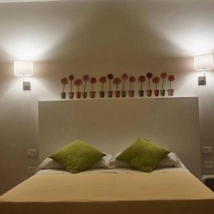 マリーナ・ディ・
スキアヴォネアにあるB&B Il Quadratoの赤い花の花瓶と緑の枕が付いたベッド