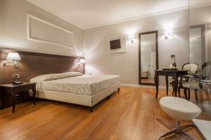 a bedroom with a bed and a table and a chair at Hotel Lombardia in Florence