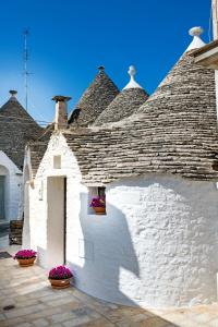 a white building with a roof with purple flowers at Trullo 11 in Alberobello