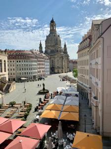 uma rua da cidade com mesas e guarda-sóis e um edifício em Familienapartment An der Frauenkirche em Dresden