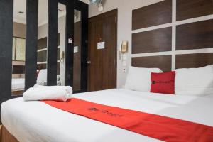 a bedroom with a large white bed with a red blanket at RedDoorz near Waterboom Lippo Cikarang in Cikarang