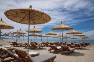 un montón de sillas y sombrillas en una playa en Mirage Hotel, en Golem