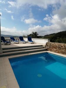 a swimming pool with blue chairs and a patio at A Quinta da Colina ( Casinha ) in Castanheira de Pêra