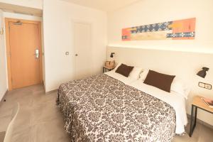a bedroom with a bed with a black and white blanket at Hotel Miami in Calella