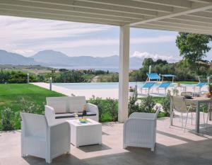 a patio with white furniture and a view of the ocean at Case Playa Resort Balestrate in Balestrate