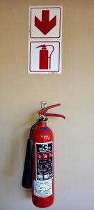 a fire extinguisher hanging on a wall with a sign at Ongegund Lodge in Somerset West