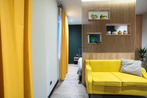salon z żółtą kanapą i żółtymi zasłonami w obiekcie Студія у центрі міста w mieście Użhorod