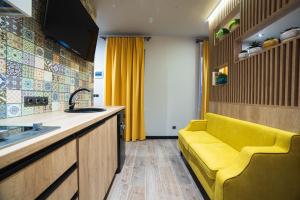 eine Küche mit einem gelben Sofa neben einem Waschbecken in der Unterkunft Студія у центрі міста in Uschhorod