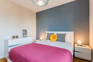 una camera da letto con un grande letto con una coperta rosa di Cascais Prime Flat a Cascais