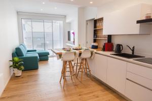 Una cocina con gabinetes blancos y una mesa y sillas. en Calabona's promenade apartment, en Alghero