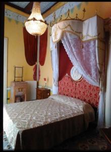 a bedroom with a canopy bed and a chandelier at Relais Palazzo del Barone, on Adriatic coast in San Martino in Pensilis