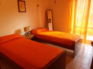 two beds in a room with orange sheets at Casa Fronte Gole Alcantara in Motta Camastra