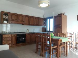 eine Küche mit Holzschränken sowie einem Tisch und Stühlen in der Unterkunft Casa Fronte Gole Alcantara in Motta Camastra