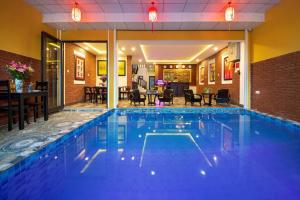 una piscina en un hotel con mesas y sillas en Hoi An Riverland Villa - Hoi An Center, en Hoi An