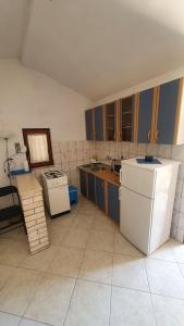 eine Küche mit blauen Schränken und einem weißen Kühlschrank in der Unterkunft Apartments Zdenka in Rogoznica