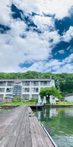 a building next to a river with a wooden dock at Nojiri Lake Resort in Shinano