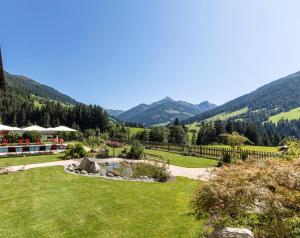 uma vista para um jardim com montanhas ao fundo em Alpbacherhof Mountain & Spa Resort em Alpbach