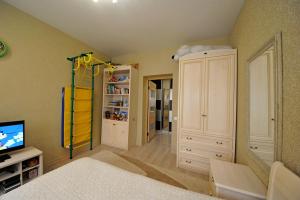 1 dormitorio con 1 cama, TV y armario en Apartments on M.Chuikova, en Volgograd