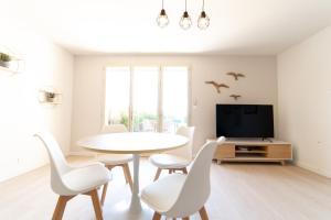 una sala da pranzo con tavolo, sedie e TV di Cottage "Le LOTUS" face au Lac de la forêt d'Orient - Les Cottages du Belvédère a Mesnil-Saint-Père