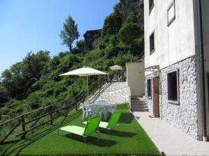 une terrasse avec des chaises vertes et un parasol dans l'établissement Il Borgo di Tresana, à Tresana