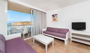 a living room with a couch and a tv at Insotel Club Tarida Playa in Cala Tarida