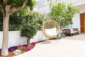 a wicker chair in a courtyard with flowers at Villa Paola by Le Dimore di Paola - Salento in Torre dell'Orso