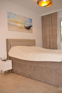 a bedroom with a large bed with a painting on the wall at Apartament Dorado in Mielno