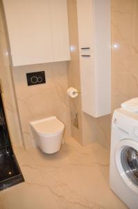 a bathroom with a toilet and a washing machine at Apartament Dorado in Mielno