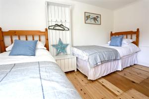 two beds in a room with wooden floors at Mackerel Cottage in Budleigh Salterton