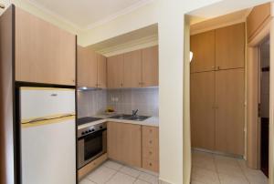 a kitchen with wooden cabinets and a white refrigerator at Delphinus Villa Nefeli in Agios Nikitas