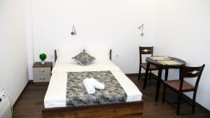 a bedroom with a bed and a table and a chair at Stenso Rooms in Pleven