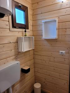 a bathroom with wooden walls and a toilet and a window at Barumi-Bungalow Michelangelo in Porlezza