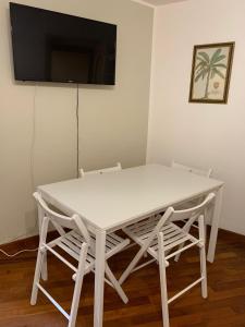 キアーヴァリにあるCasa Entella by Vacanze in Chiavariの白いテーブルと椅子(壁にテレビ付)