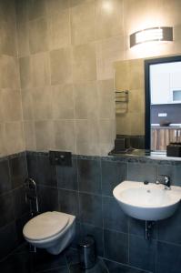 a bathroom with a sink and a toilet and a mirror at Stenso Rooms in Pleven