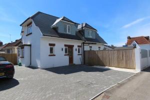 a white house with a fence and a driveway at 3 Bedroom Detached Beach House Poole in Poole
