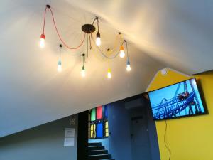 a group of lights hanging from a ceiling with a tv at Kapsuła Hostel in Zator