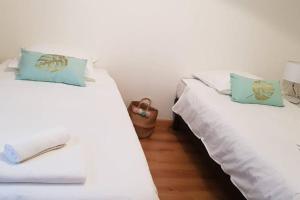 2 łóżka w pokoju z białą pościelą i niebieskimi poduszkami w obiekcie Le Gite de Myla au pied du Château Royal d'Amboise w mieście Amboise