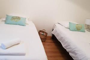 two beds in a room with white sheets and blue pillows at Le Gite de Myla au pied du Château Royal d'Amboise in Amboise