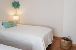 - un lit blanc dans une chambre avec une lampe et un panier dans l'établissement Le Gite de Myla au pied du Château Royal d'Amboise, à Amboise