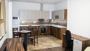 a kitchen with wooden cabinets and a table and chairs at Stenso Rooms in Pleven