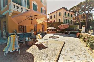 a patio with an umbrella and chairs and a building at Grande appartamento in Villa con terrazza sul mare in Celle Ligure