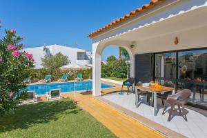 een patio met een tafel en stoelen naast een zwembad bij Villa Jorge by Villa Plus in Albufeira