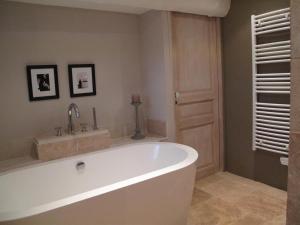 uma casa de banho com uma grande banheira branca e um lavatório. em Le Mas de l'Olivier em Loriol-du-Comtat
