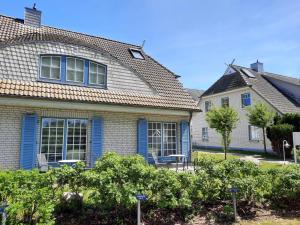 ein Haus mit blauen Fenstern und Büschen davor in der Unterkunft Ferienwohnung #20 Am Neuensiener See - Seedorf in Sellin