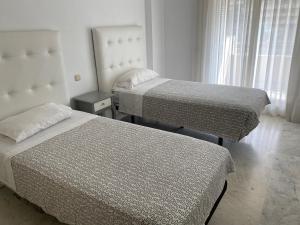 マルベーリャにあるMarina Banusのベッド2台と窓が備わる客室です。