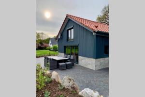 a blue house with a patio and a table at neue ruhige Ferienwohnung am Wald in Wüstewohlde