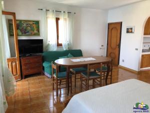 a room with a table and a couch and a television at Magi - Il Tramonto su Palmarola in Ponza