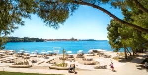people walking around a beach with a body of water at Maistra Select Family Hotel Amarin in Rovinj