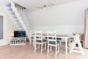 ein weißes Zimmer mit einem Tisch, Stühlen und einer Treppe in der Unterkunft Ferienhaus Windspiel in Neuharlingersiel